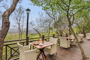 Un área de comedor al aire libre con mobiliario de mimbre y vistas al paisaje.
