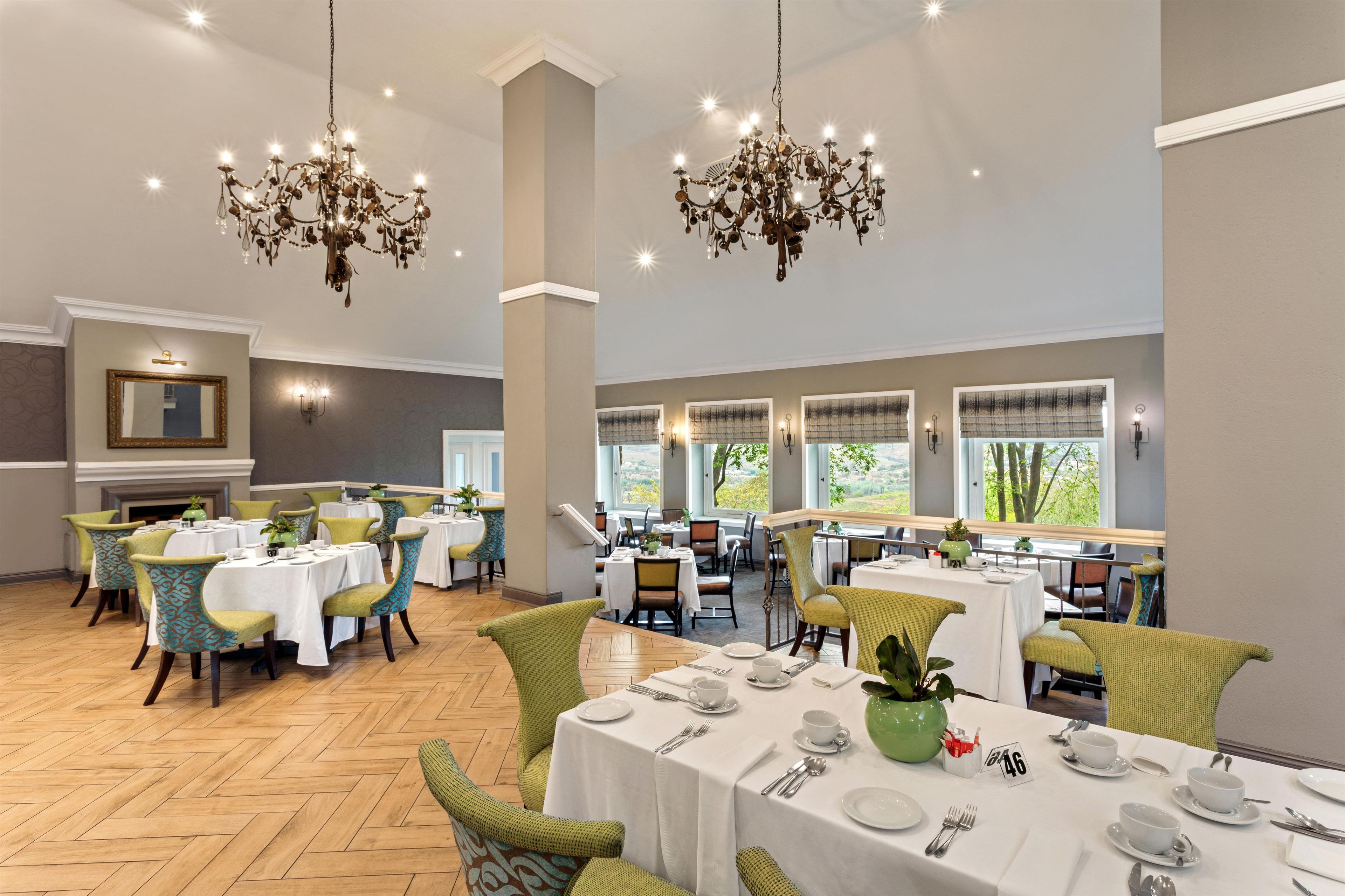 A spacious dining area with multiple tables, chairs, and chandeliers.