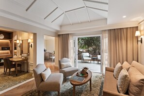 A hotel room with a seating area, a dining area, and a view of the outdoors.