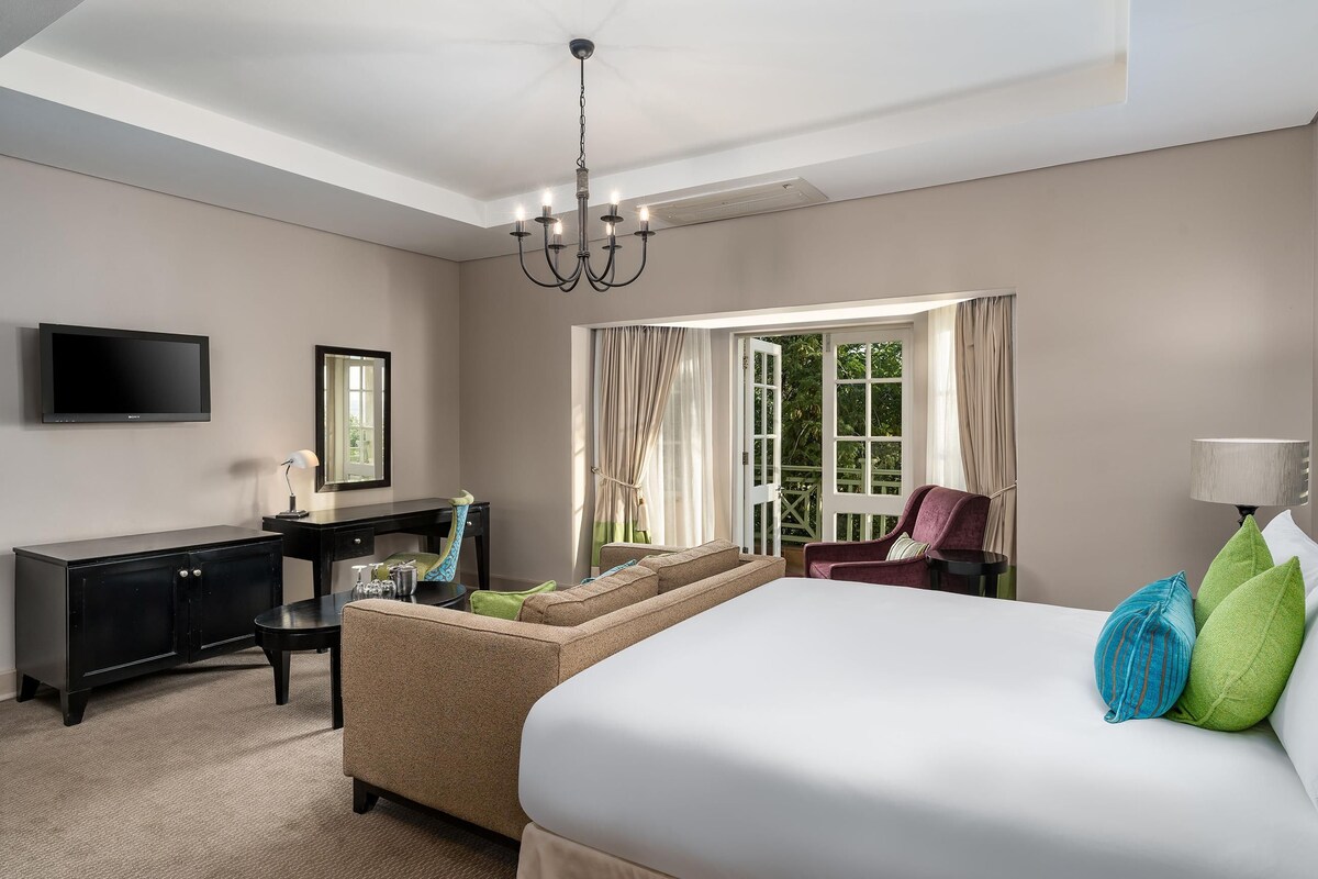 A hotel room with a bed, a desk, a chair, a television, and a window with curtains.