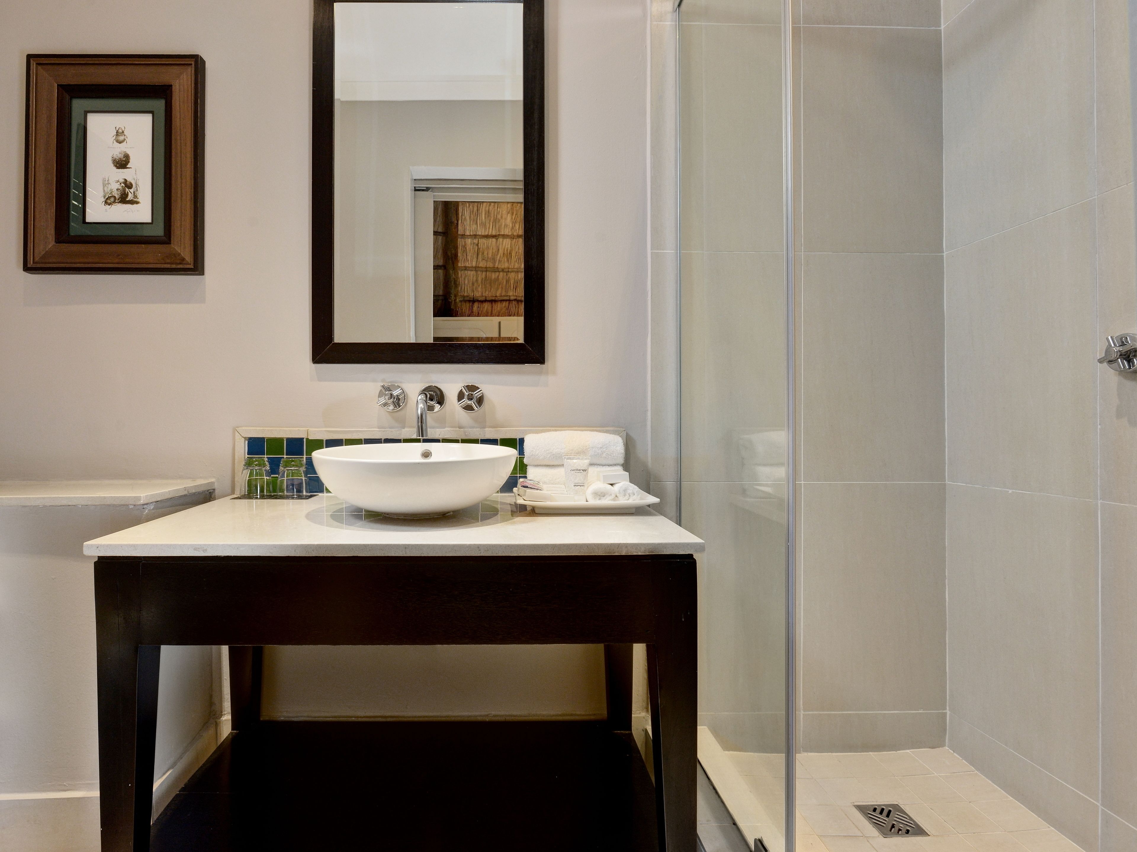 A bathroom with a white sink, a mirror, and a glass shower enclosure.