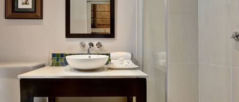 A bathroom with a white sink, a mirror, and a glass shower enclosure.