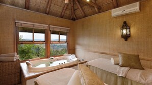 A spa room with a large bathtub, a cushioned seating area, and a view of the outdoors. - Mount Grace Hotel & Spa (Magaliesberg)