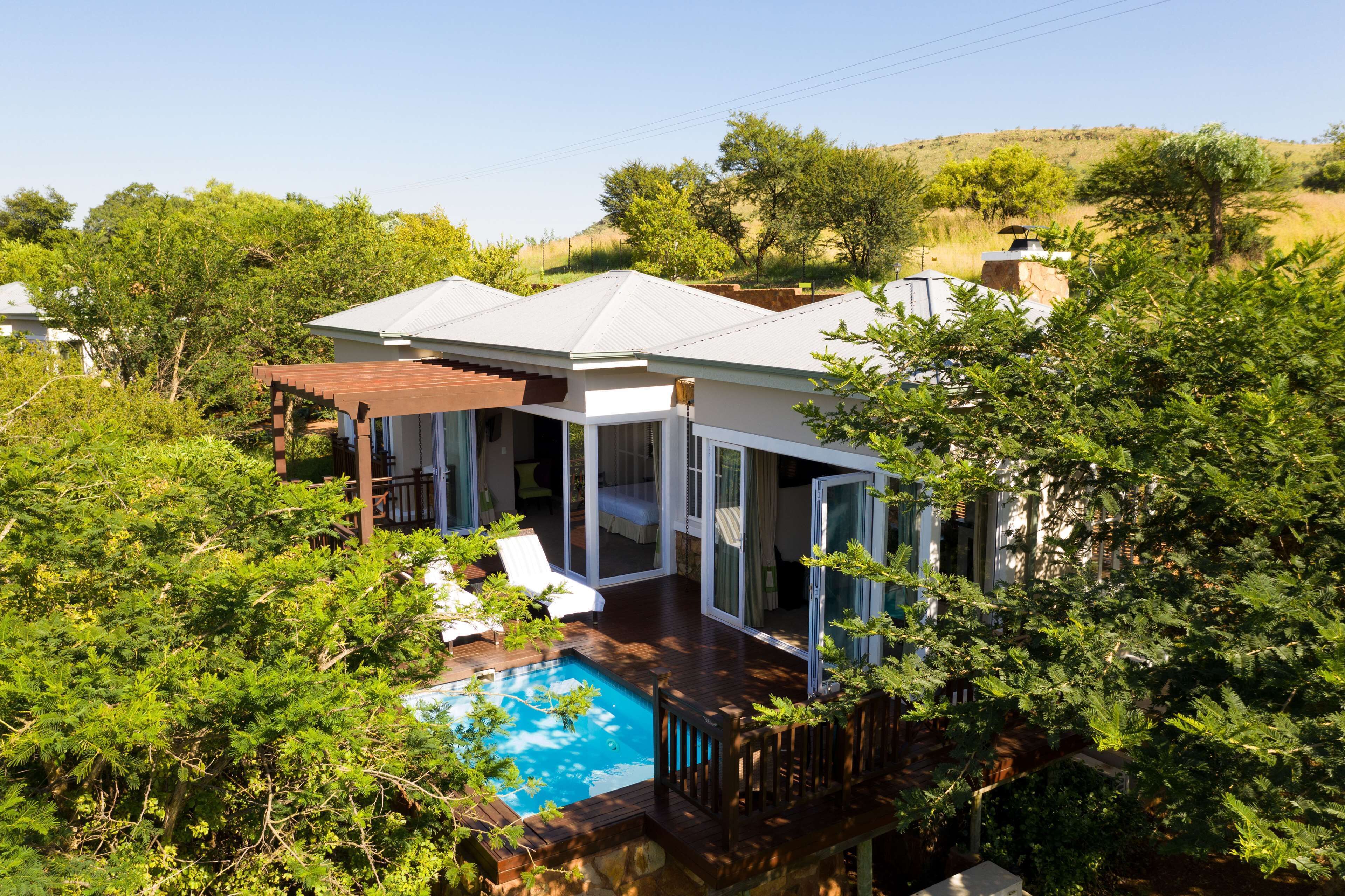 A house with a swimming pool, large windows, and a deck.