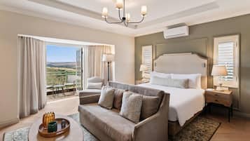 Habitación de hotel con una cama grande, un sofá, una mesa de comedor y vistas al exterior.
