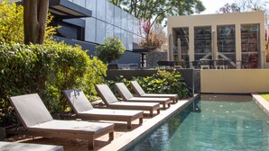 A pool area with lounge chairs and a modern building in the background. - Ten Bompas (Randburg)