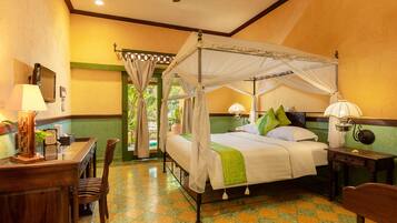 A room with a four-poster bed, a desk with a lamp, and a chair.