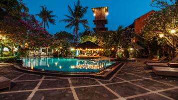 Een buitenzwembad, ligstoelen bij het zwembad