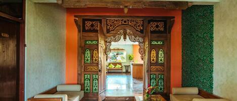 A traditional room with a wooden sofa set, a small table, and a decorative entrance with intricate designs.