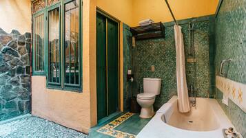 A bathroom with a bathtub, toilet, and shower area.