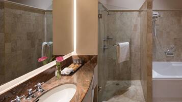 A modern bathroom with a glass-enclosed shower, a white bathtub, and a marble countertop with a sink and vanity.