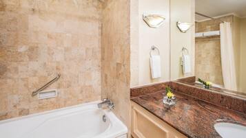 Une salle de bain équipée d’une baignoire, d’un lavabo, d’un meuble-lavabo et d’un grand miroir.