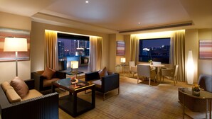 A hotel room with a city view, a dining area, and a seating area with a coffee table and chairs.