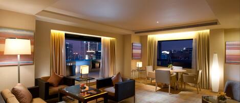 A hotel room with a city view, a dining area, and a seating area with a coffee table and chairs.