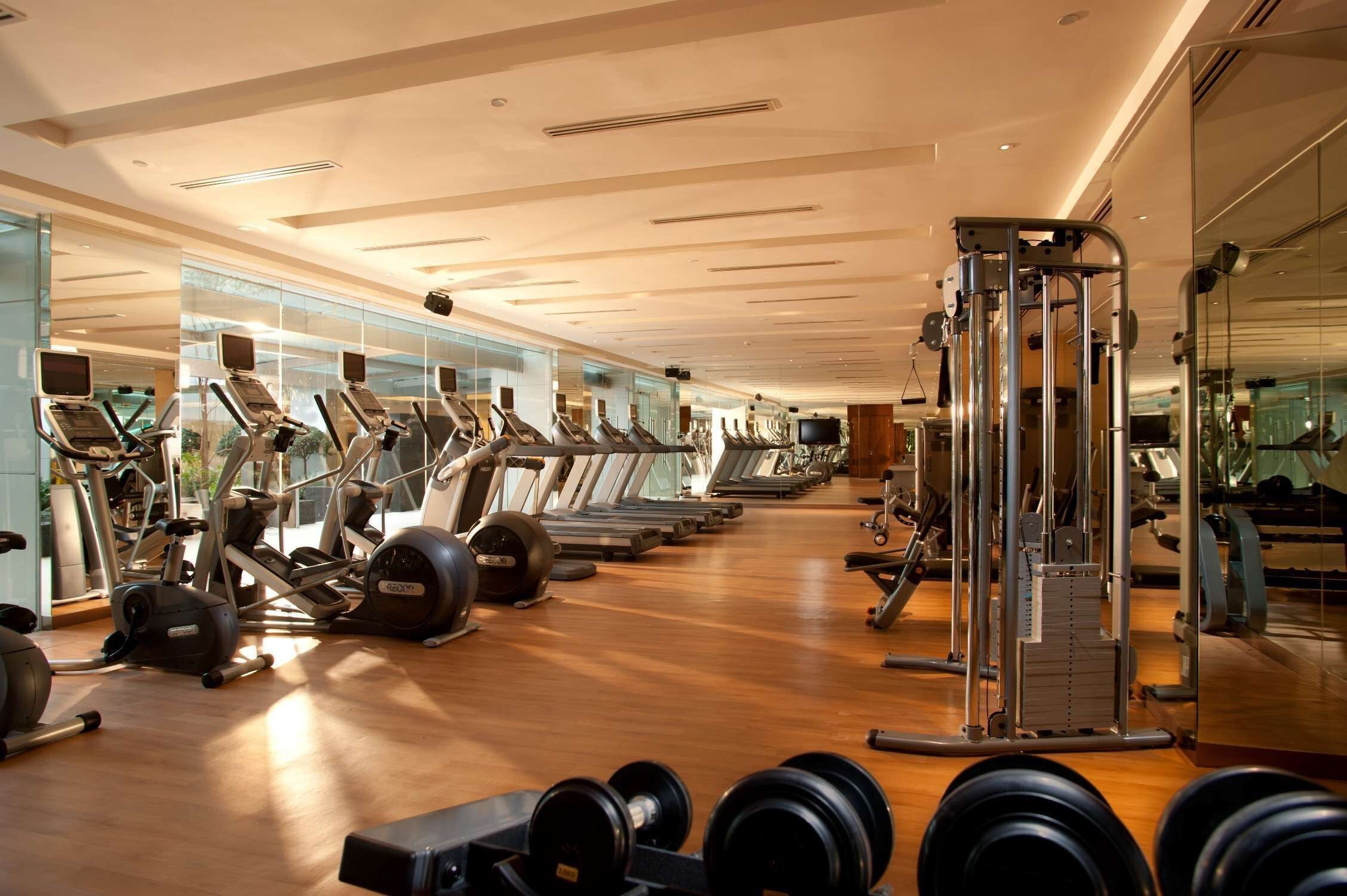 A gym with treadmills, elliptical machines, and weightlifting equipment.