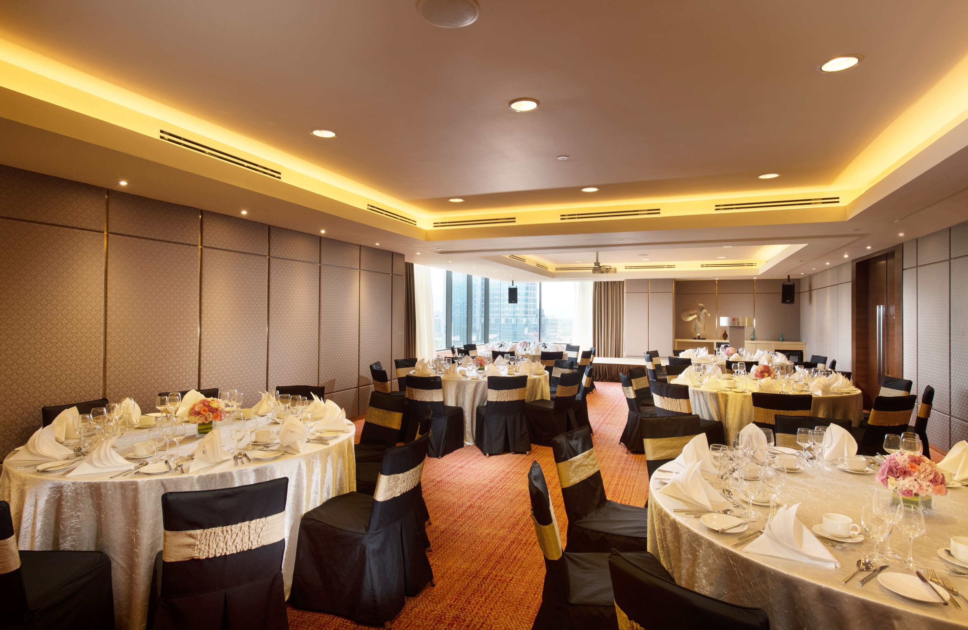 Una sala da banchetti con tavoli rotondi apparecchiati per la cena, completa di sedie e tovagliato.
