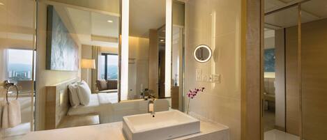 Une salle de bain moderne avec un grand miroir, un lavabo rectangulaire et un vase rempli de fleurs.