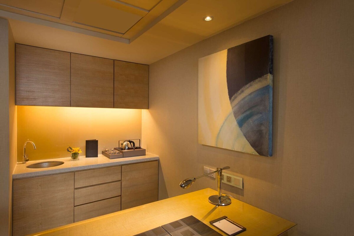 A modern bathroom with a sink, mirror, and a painting on the wall.
