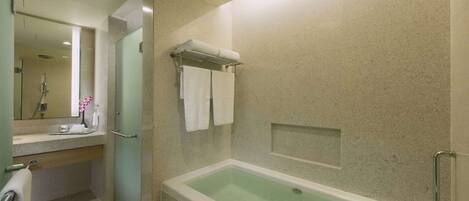Un baño moderno con una bañera, un tocador con espejo y un perchero para toallas.
