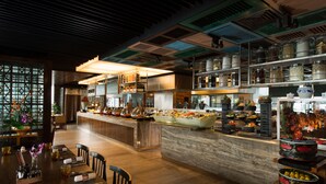 A modern restaurant with a central bar area, wooden flooring, and a variety of food displays.
