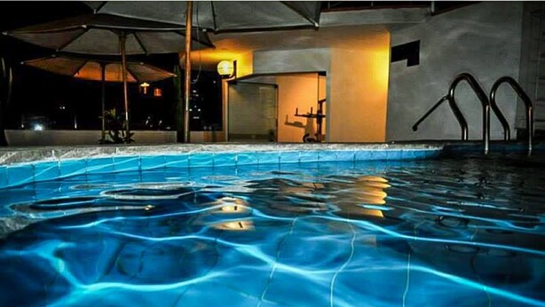 Une piscine à l’eau claire, un banc encastré et un espace de détente avec des parasols.