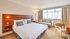 A hotel room with a large bed, a sofa, a chair, and a small table. - Palms Hotel & Retreat By Palette London Romford (Hornchurch)