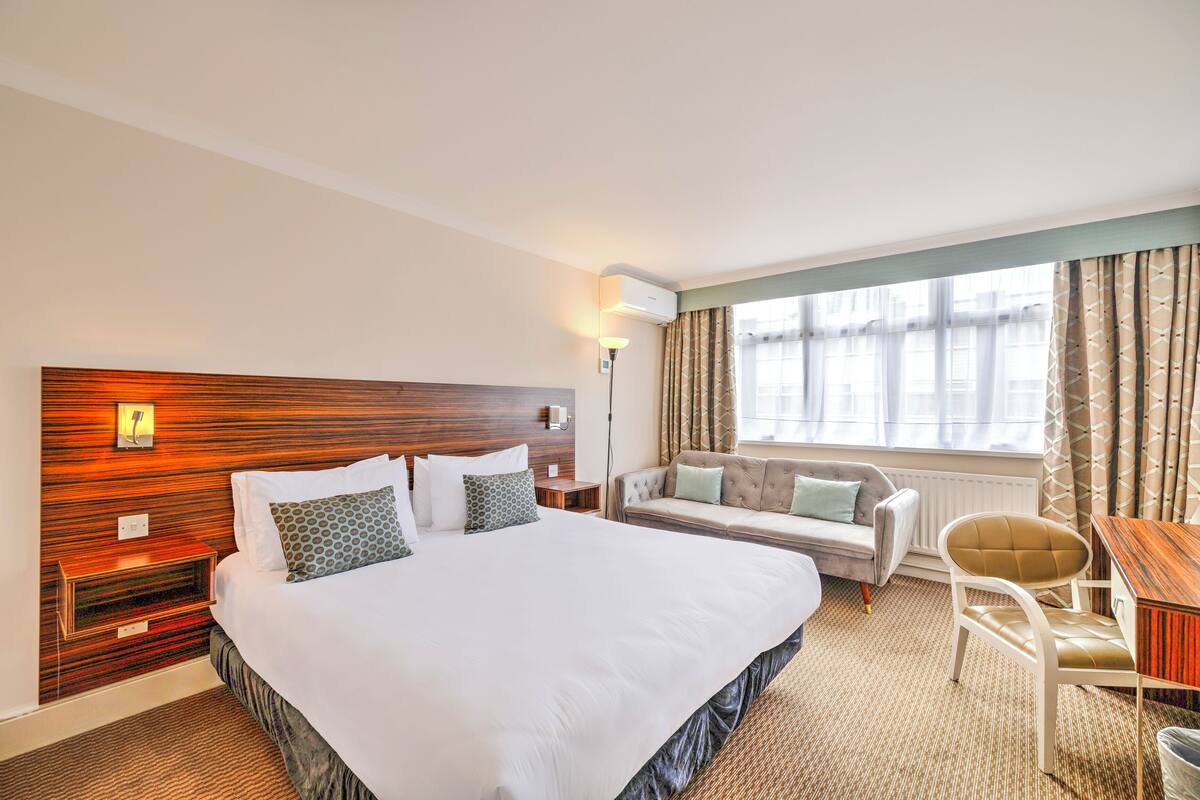 Una habitación de hotel con una cama grande, un sofá, una silla y una mesita.