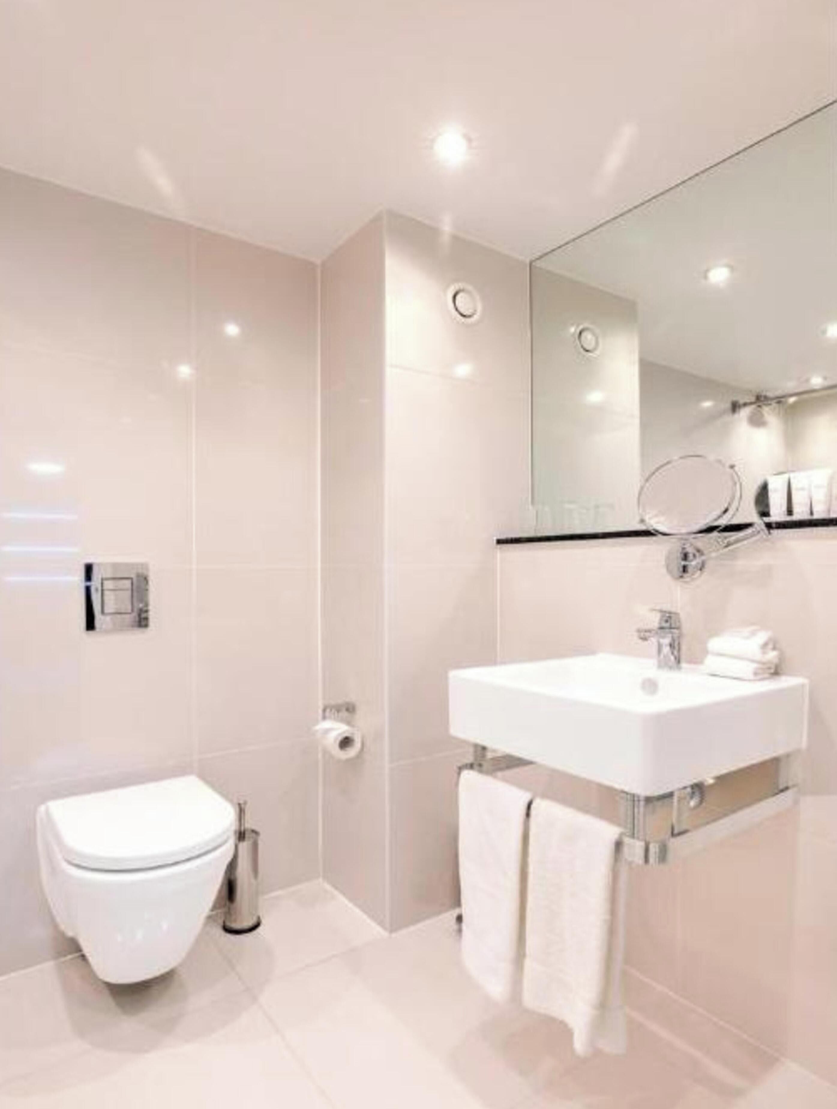 A modern bathroom with a toilet, sink, and shower.