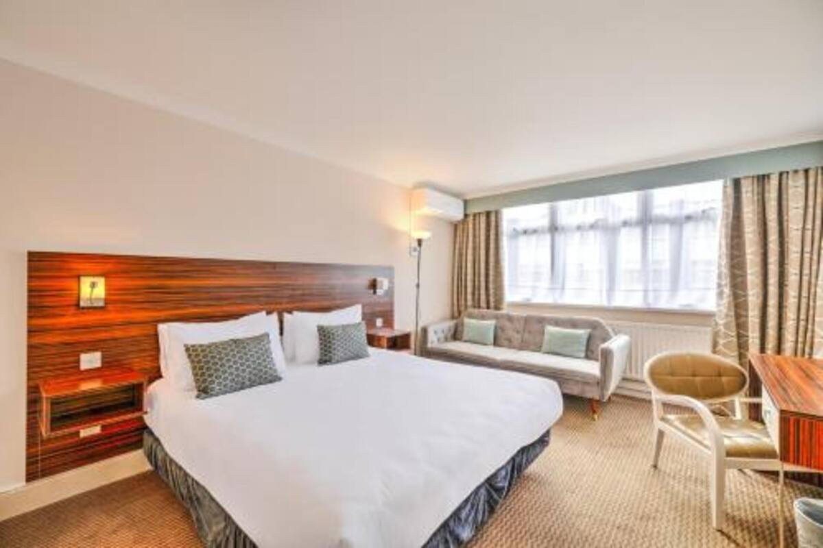 Una habitación de hotel con una cama grande, un sofá, una silla y una mesita.