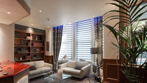 A modern living room with a glass coffee table, two sofas, a bookshelf, and a red table. - Henley House Hotel (London)