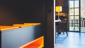 A modern interior with a dark wall, a wooden floor, and a seating area with a table and chairs. - Domaine du Blé Hôtel (Wavre)