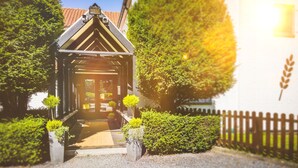 A traditional building with a gabled entrance, surrounded by well-maintained hedges and a wooden fence. - Domaine du Blé Hôtel (Wavre)