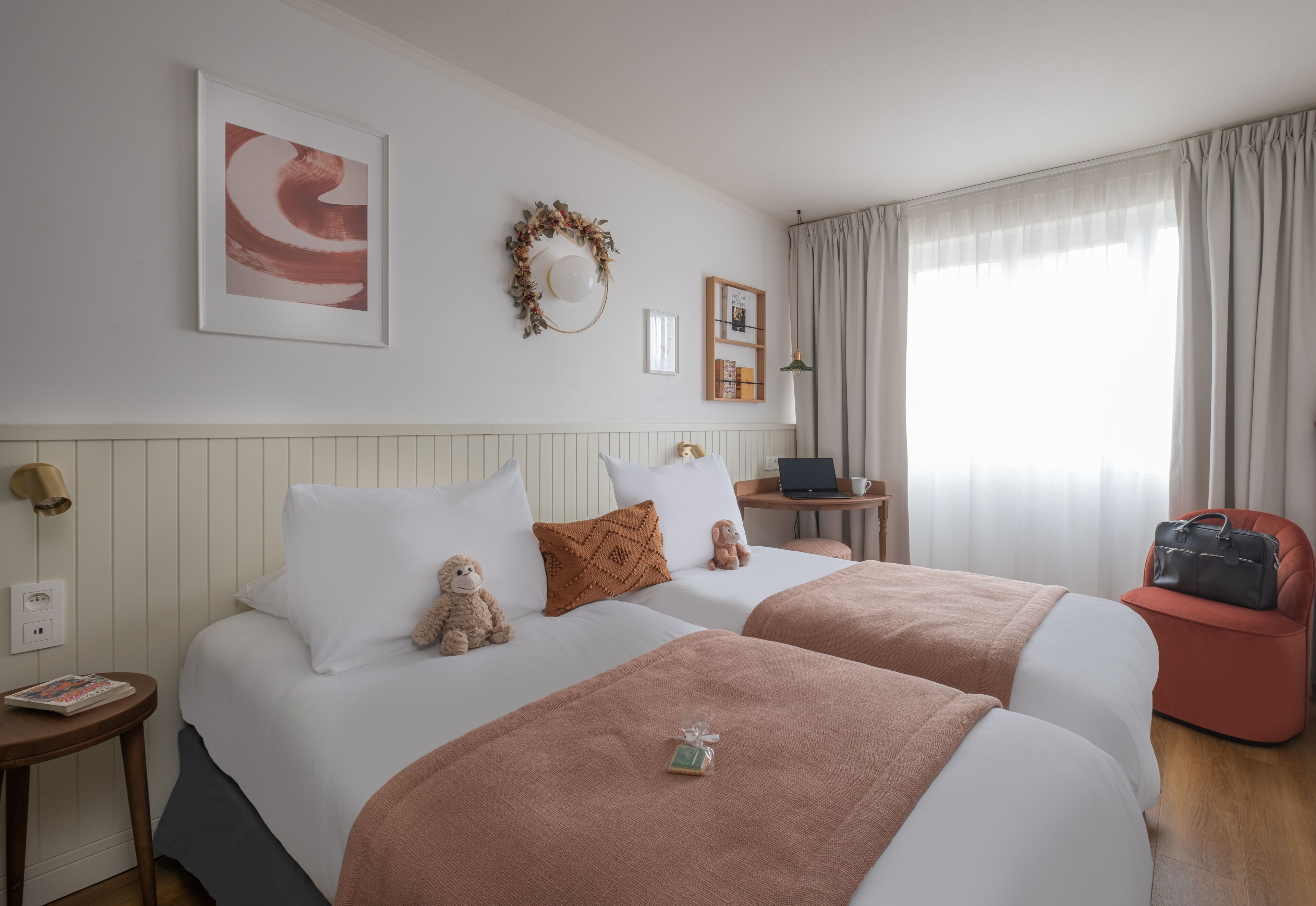Una habitación de hotel con dos camas, un escritorio, una silla y una ventana con cortinas.