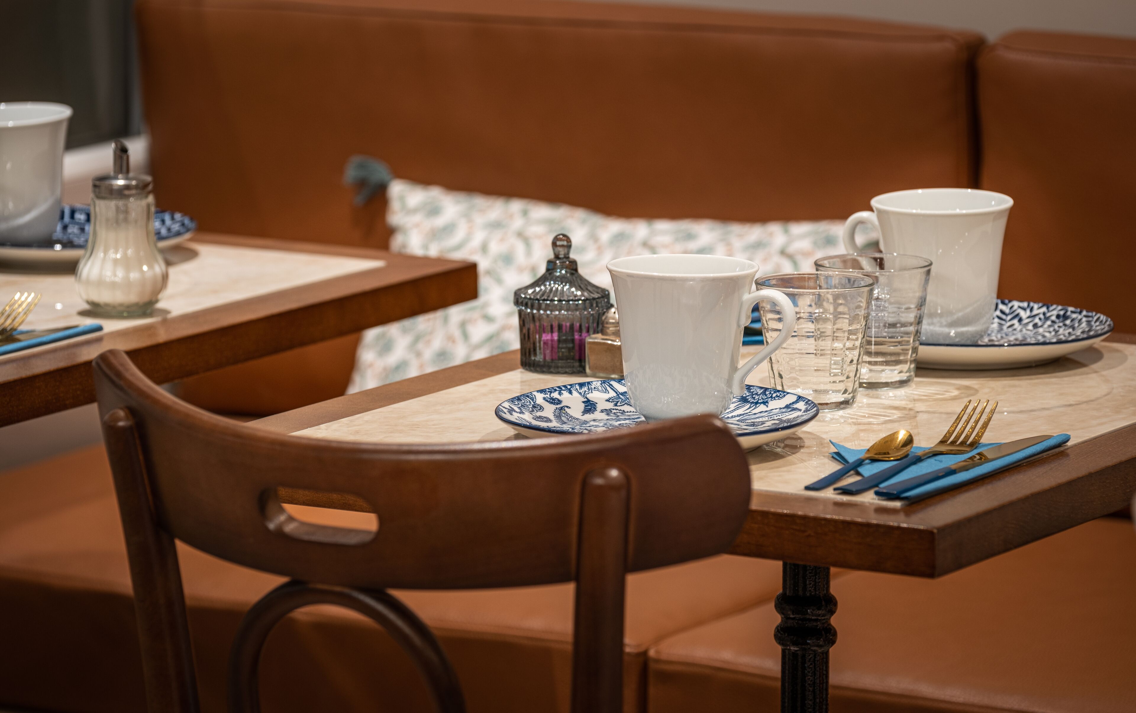 Un comedor con una mesa lista para dos personas, con una jarra, tazas y vasos.