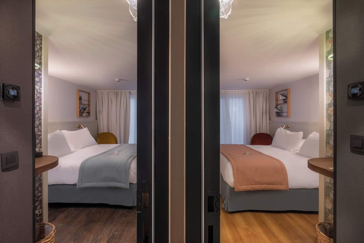 A mirrored room with two beds, a wooden floor, and a ceiling light fixture.