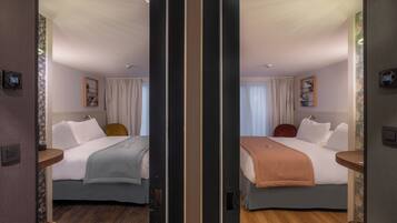 Une pièce aux murs recouverts de miroirs, avec deux lits, un plancher en bois et un luminaire au plafond.