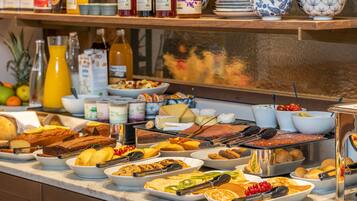 A buffet with various food items including cakes, pastries, and fruits.