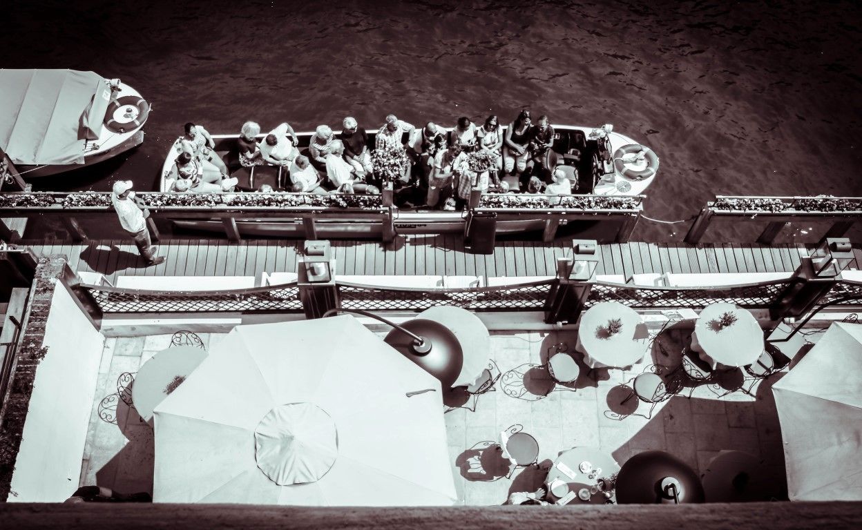 Un bateau avec des personnes à bord, entouré de parasols et doté d’une rambarde en filet.