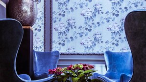 A room with two blue chairs, a large vase with flowers, and a floral wallpaper pattern. - Hotel de Orangerie by CW Hotel Collection - Small Luxury Hotels of the World (Bruges)