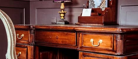 Un escritorio de madera con varios cajones, una lámpara y un cuadro enmarcado.