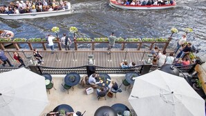 Un restaurante junto al río con terraza, un muelle con barcos y vistas al agua.