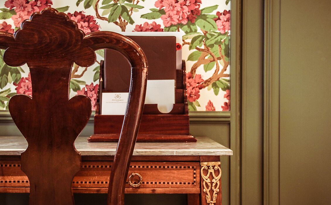 A wooden desk with a carved backrest and a drawer with a ring handle.