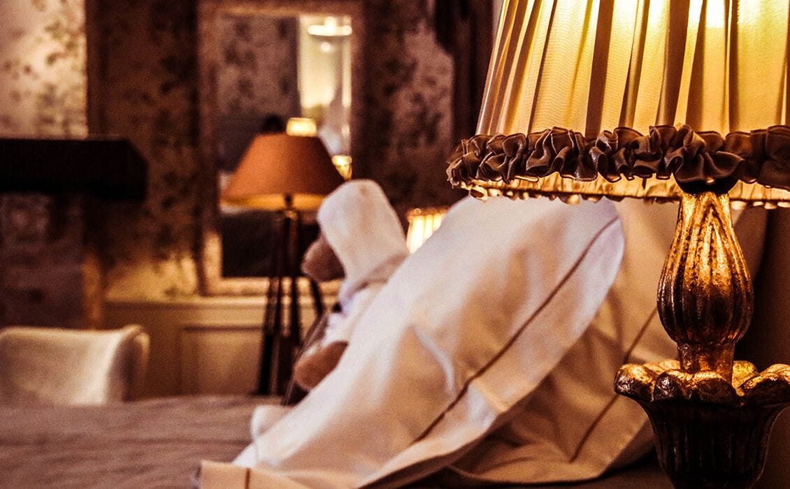 Ein Zimmer mit einem Bett, einer Lampe und einem Sessel.