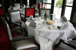 A dining table set for four with white tablecloths, silverware, and wine glasses. - Palladia Hotel (Toulouse)