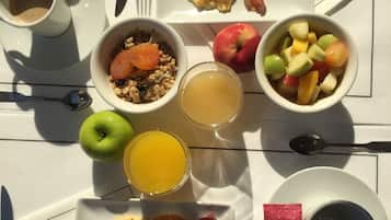 Una mesa de desayuno con diversos alimentos, como huevos, tocino, salchichas, tostadas, fruta y un muffin.
