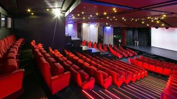 A theater with rows of red seats, a stage, and a ceiling with star-shaped lights.