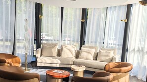 A modern living room with a beige sofa, brown leather armchairs, and a wooden coffee table. - Palladia Hotel (Toulouse)