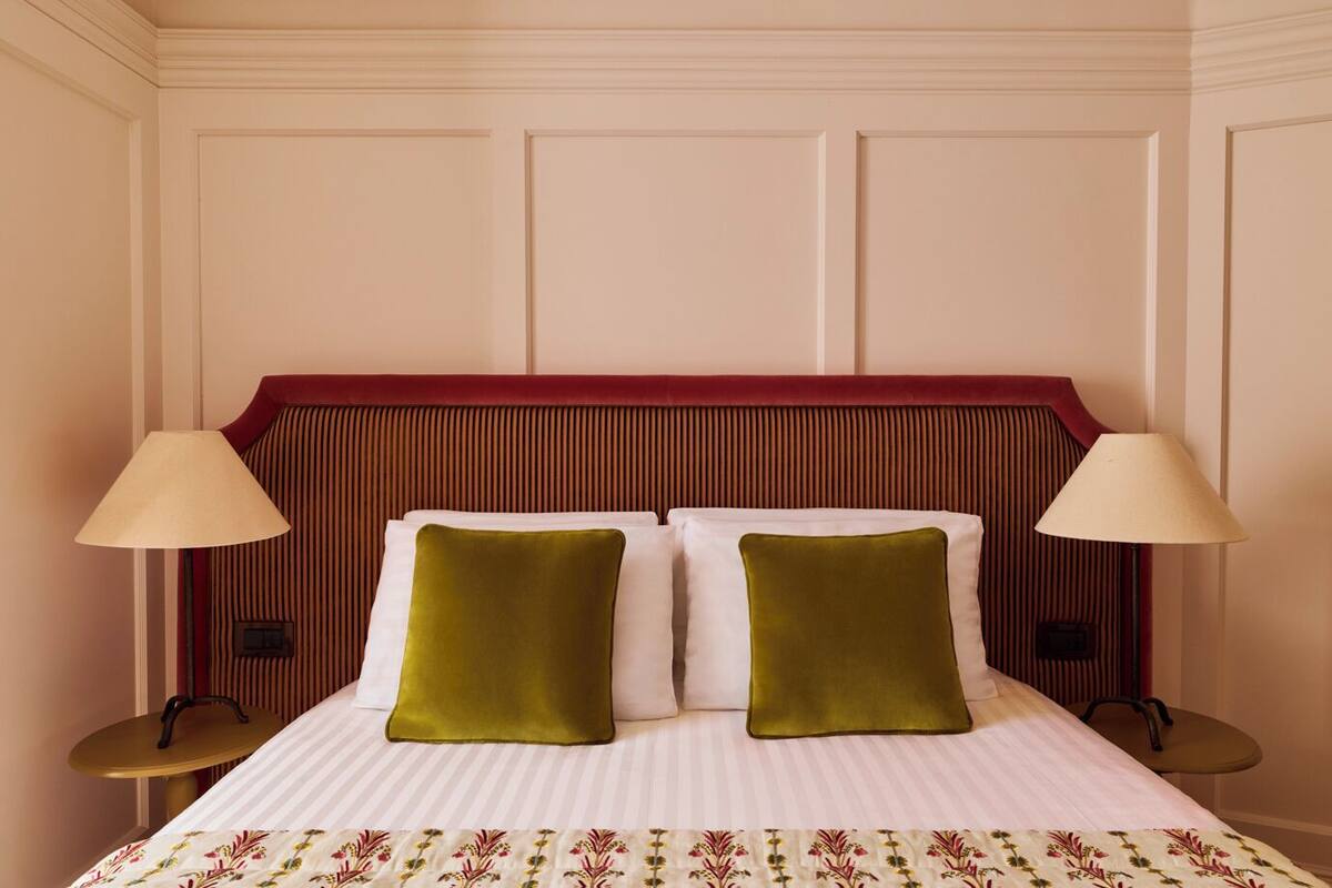 A hotel room with a bed, two bedside lamps, and a floral-patterned bedspread.