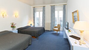 A hotel room with two beds, a desk with a lamp, a chair, and a window with curtains. - Hostel Toulouse Wilson (Toulouse)