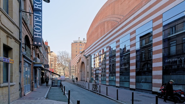 A street view with a hotel named "HOTEL ROYAL" on the left, a modern building with reflective windows on the right, and a clear sky. - Hostel Toulouse Wilson (Toulouse)